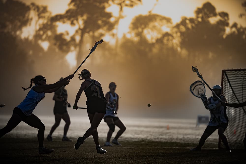 Lacrosse player driving on goal through a golden morning fog